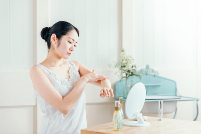 不満そうに腕を触る女性　写真